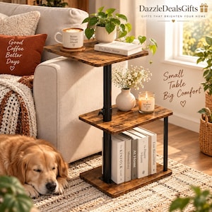 May include: A two-tier side table with a dark brown wood-grain finish and a black metal frame. The top shelf holds a white mug, a book, and a potted plant. The bottom shelf holds a white vase with flowers, a candle, and several books.