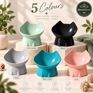 May include: Five cat-shaped pet bowls in mint green, black, grey, blue-teal, and pink. Each bowl features a raised base with small paw details at the bottom. Text on the image includes 5 Colours, Same Happy Bowl, Different Vibes, and RoversStore.
