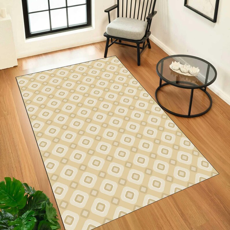 May include: A rectangular area rug featuring a repeating geometric pattern of rounded squares in shades of beige, cream, and light brown. The rug is laid flat on a wooden floor, showcasing a consistent grid design across its entire surface area.