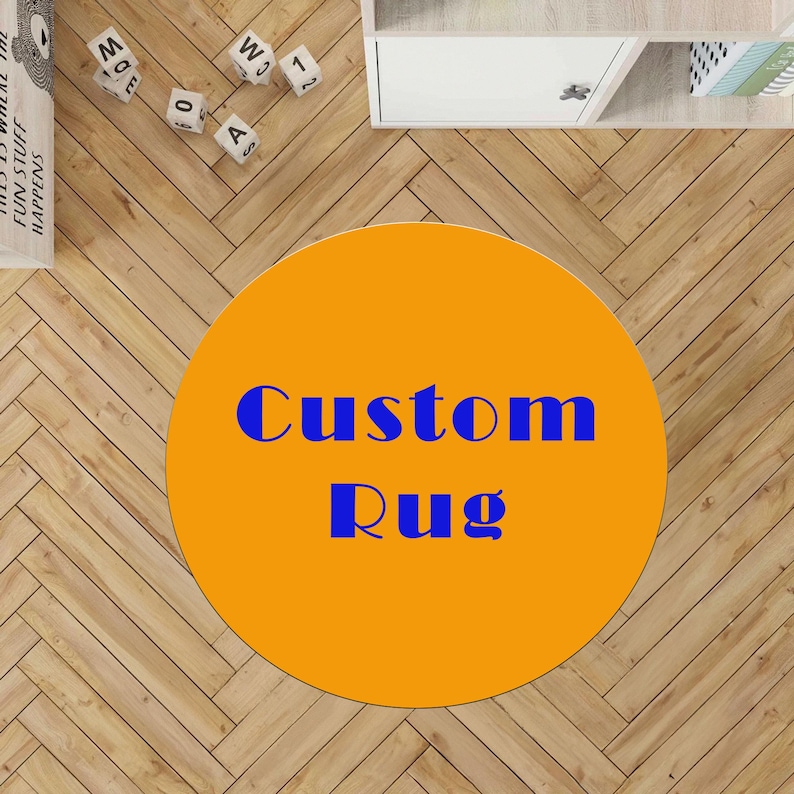 May include: An orange circular rug with the words "Custom Rug" in blue. The rug is on a light brown wooden floor. The image also shows a white shelf and some decorative blocks.