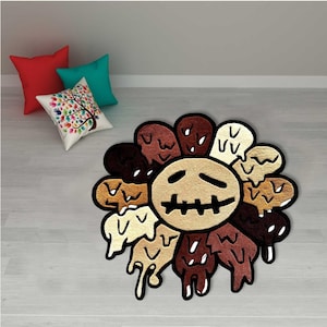 May include: A unique, decorative rug in the shape of a sunflower with a distressed face design. The rug features a variety of brown and beige tones, with a black outline. The rug is placed on a light-colored wooden floor. Three throw pillows are in the background.