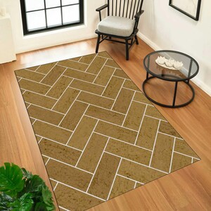 May include: A rectangular area rug featuring a repeating herringbone pattern in a textured mustard yellow tone with thin white grout lines between each rectangular segment, creating a visual effect similar to a brick or tile floor layout.