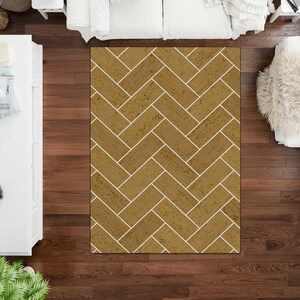 May include: A rectangular area rug featuring a repeating herringbone pattern. The rug consists of golden-brown, textured rectangular segments separated by thin, crisp white lines, creating a structured geometric design across the entire surface.