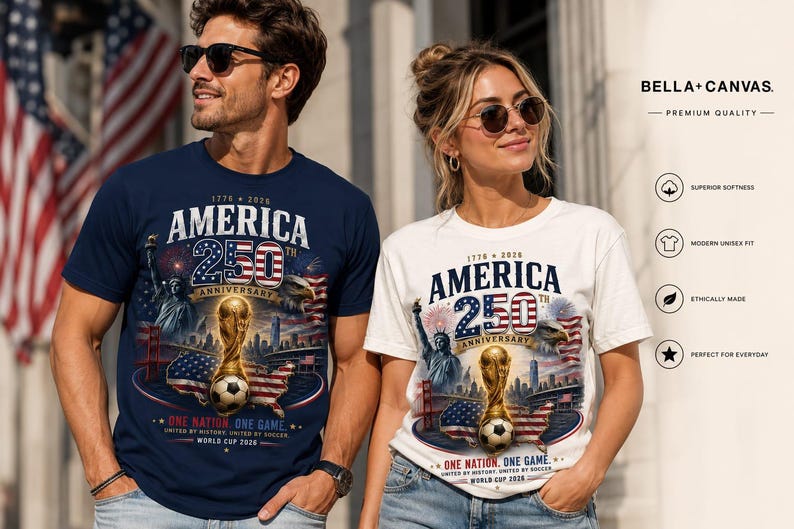 K&ouml;nnte beinhalten: Ein marineblaues T-Shirt und ein wei&szlig;es T-Shirt, beide mit einem Grafikdruck mit der Aufschrift America 250th Anniversary, 1776-2026, One Nation, One Game, World Cup 2026, mit einem Fu&szlig;ballpokal, einem Fu&szlig;ball, der Freiheitsstatue und einer US-Flagge.