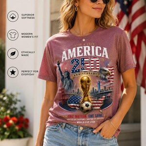 K&ouml;nnte beinhalten: Ein kurz&auml;rmeliges T-Shirt in meliertem Kastanienbraun mit einem Grafikdruck, der den Text AMERICA 250TH ANNIVERSARY, eine goldene Troph&auml;e, einen Fu&szlig;ball, die Freiheitsstatue, einen Wei&szlig;kopfseeadler und eine Karte der USA zeigt.