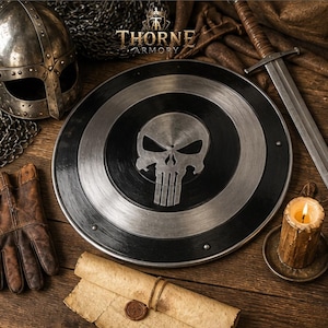 Puede incluir: Un escudo circular de metal con un emblema central de calavera plateada sobre un fondo negro y de acero cepillado. El escudo está rodeado por un casco de metal, una espada, guantes de cuero marrón, un pergamino enrollado y una vela encendida.