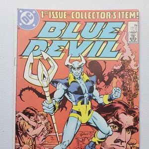May include: A vintage comic book cover featuring the Blue Devil character. The cover art showcases a muscular, blue-skinned figure with horns, holding a trident. The title "BLUE DEVIL" is prominently displayed in bold, blue letters. The comic is labeled "1st Issue - Collector's Item!"