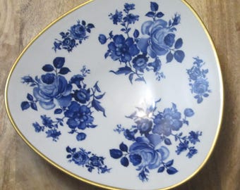 Könnte beinhalten: Weiße Keramik-Servierschale mit goldenem Rand und blauem Blumenmuster. Die Schale hat eine asymmetrische Form und zeigt blaue Rosen und andere Blumen. Ein dekoratives Stück zum Servieren von Speisen.