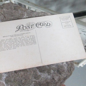 May include: Vintage postcard with a black and white photo of the Alamo, a historic building in San Antonio, Texas. The back of the postcard has text about the Alamo's history and a place for a stamp.
