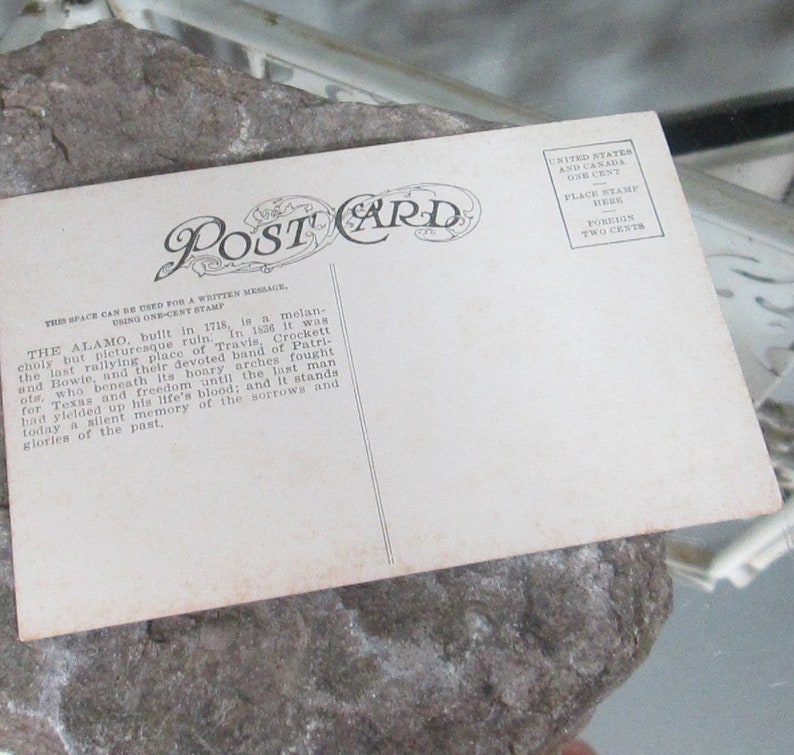 May include: Vintage postcard with a black and white photo of the Alamo, a historic building in San Antonio, Texas. The back of the postcard has text about the Alamo's history and a place for a stamp.