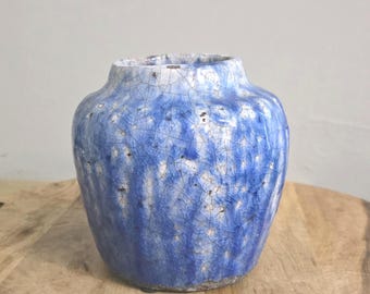 Könnte beinhalten: Eine Keramikvase mit bauchigem Körper und kurzem, weitem Hals. Die Außenseite ist mit einer leuchtend blauen Glasur überzogen, die ein ausgeprägtes weißes Craquelé-Muster aufweist und eine strukturierte Oberfläche mit dunklen Flecken zeigt.