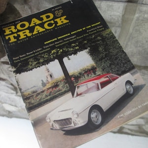 May include: A vintage magazine cover featuring a white Fiat-O.S.C.A. 1500 by Farina car with a red roof. The magazine is titled "Road & Track" and the cover text includes "The Motor Enthusiasts' Magazine" and "Complete Technical Analysis of the Valiant".