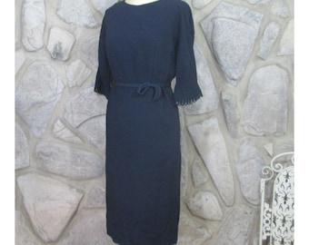 Könnte beinhalten: Ein dunkelblaues Kleid mit figurbetonter Silhouette und einem Bindegürtel. Das Kleid hat kurze Ärmel mit einer gekräuselten Kante.