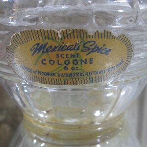 Puede incluir: Una botella de vidrio transparente con una superficie texturizada. La botella tiene una etiqueta amarilla con ribete azul y negro. La etiqueta dice "Mexicali Spice Scent Cologne 6 oz. House of Pickwick Distributors - Fifth Ave. New York."