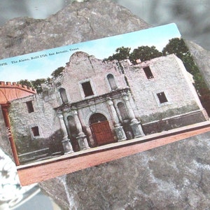 May include: A vintage postcard depicting The Alamo, a historic mission in San Antonio, Texas. The postcard features a photo of the building's facade, with its whitewashed walls, arched doorways, and small windows. The text on the postcard reads "7578. The Alamo. Built 1718. San Antonio, Texas."