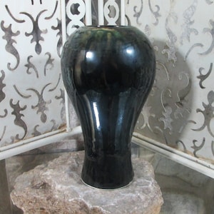 May include: A black ceramic vase with a glossy finish. The vase has a rounded body and a flared base.