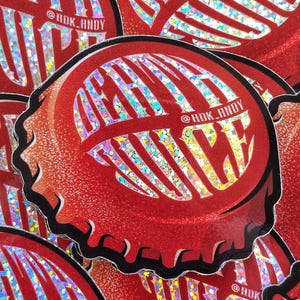 Könnte beinhalten: Roter Flaschenverschluss-Aufkleber mit glitzerndem, holografischem Design. Der Aufkleber zeigt den Text "SUNDAY" in einer stilisierten Schriftart. Der Aufkleber hat einen schwarzen Rand und den Text "@HDK_ANDY".