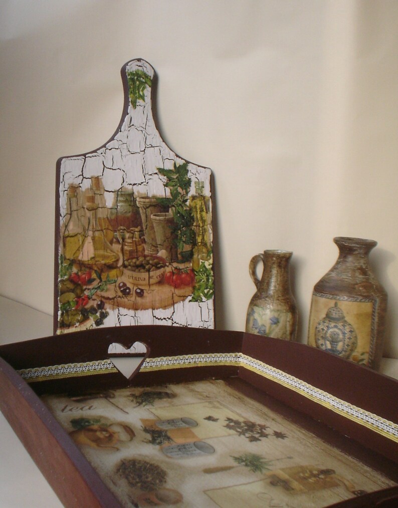 May include: A decorative wooden serving tray and cutting board with a rustic, crackled finish. The tray features a heart-shaped cutout and a decorative border. The cutting board and tray are decorated with images of olives, bottles, and herbs.
