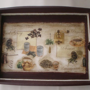 May include: A rectangular wooden serving tray with a dark brown border and heart-shaped cutouts on the sides. The tray's surface features a tea-themed design with illustrations of tea leaves, cups, a teapot, and a grinder. The words "Earl Grey", "Darjeeling", "Assam", and "Lapsang souchong" are also visible.