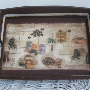 May include: A rectangular brown serving tray with a decorative tea-themed design. The tray features images of tea leaves, teacups, a teapot, and a coffee grinder. The words "Earl Grey", "Assam", and "tea" are visible on the tray.