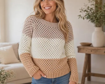 May include: A long-sleeve crochet sweater featuring a color-blocked design with horizontal stripes in shades of light brown, cream, and tan. The garment has a round neckline, ribbed cuffs, and a ribbed hem, constructed with a repeating open-work pattern.