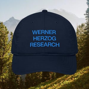 Peut inclure: Une casquette de baseball bleu marine avec le texte WERNER HERZOG RESEARCH brodé en fil bleu vif sur le panneau avant. La casquette présente une calotte structurée, une visière incurvée et un bouton au sommet du dôme en tissu.