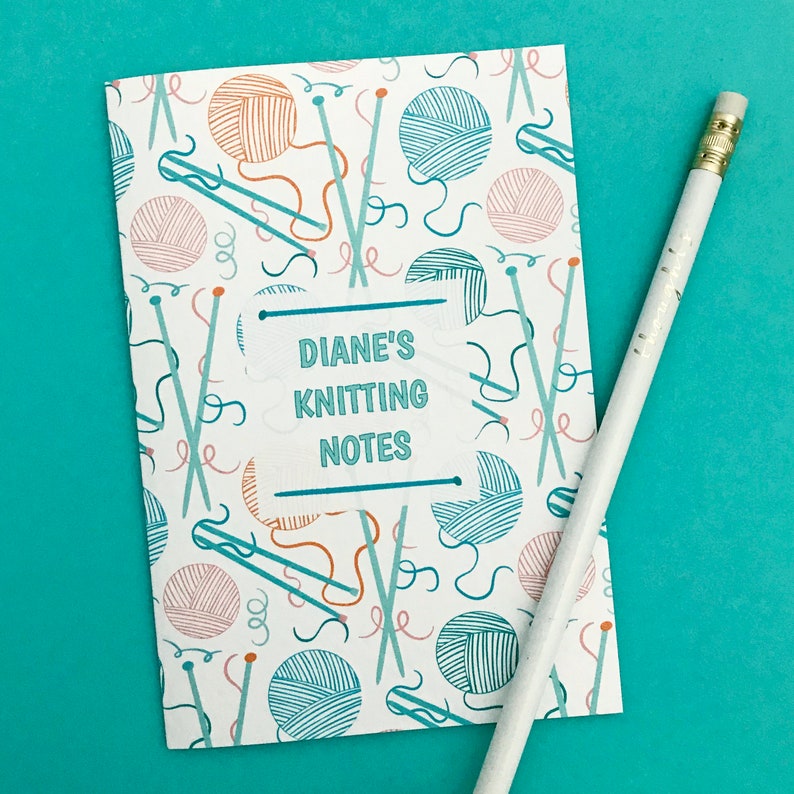 May include: A white notebook with a blue and orange knitting pattern. The notebook has a label that says "Diane's Knitting Notes".