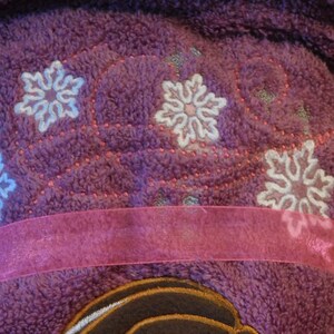 May include: Purple fleece robe with a pink ribbon and embroidered snowflakes.