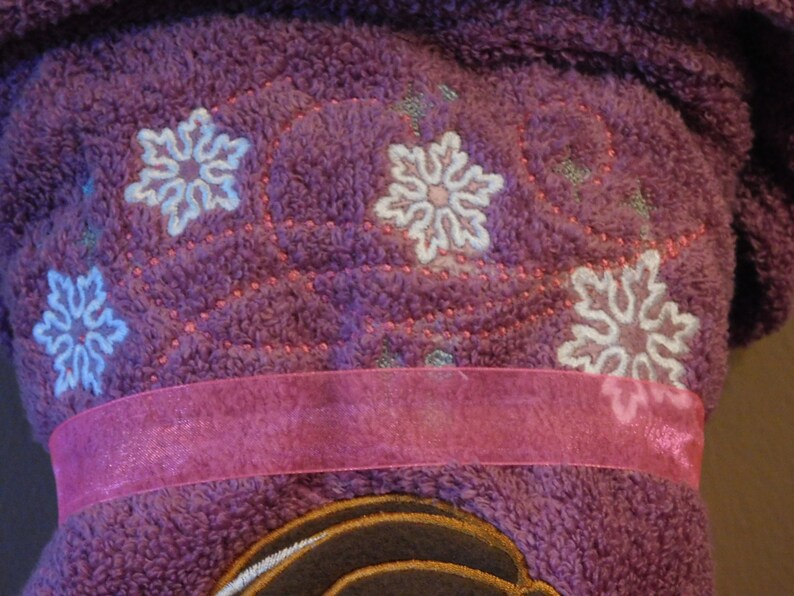 May include: Purple fleece robe with a pink ribbon and embroidered snowflakes.