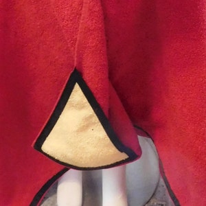 Puede incluir: Una tela de tejido polar rojo con ribete negro y forro amarillo. La tela est&aacute; doblada por la mitad y el forro es visible en el interior del pliegue.