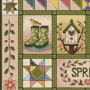 Op de afbeelding: Een kruissteekpatroon met een raster van seizoensgebonden motieven, waaronder een gele vogel op groene regenlaarzen, een vogelhuisje met roze bloesems, een veelkleurige ster en een rank met roze bloemen, omlijst door een donkergroene rand.