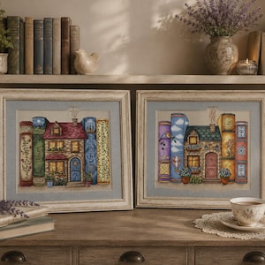 Può includere: Due opere d'arte a punto croce incorniciate raffigurano case immerse tra pile di libri. Le case hanno tetti rossi e facciate dettagliate. I libri sono colorati, con disegni floreali e motivi. Le cornici sono bianco sporco con finitura anticata.