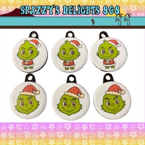 May include: Six circular white ornaments featuring a green character wearing a red and white Santa hat. The top row shows the character standing with arms crossed, while the bottom row shows the character's face. Text at the top reads SPAZZY'S DELIGHTS 808.