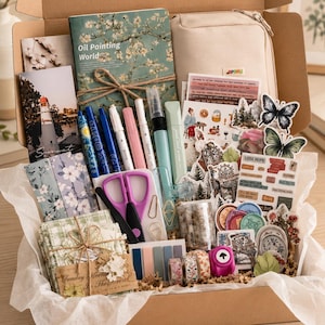 May include: A cardboard gift box filled with stationery supplies including a floral notebook labeled Oil Painting World, a beige pencil case, various pens, purple scissors, decorative stickers, washi tape rolls, and small paper note cards.