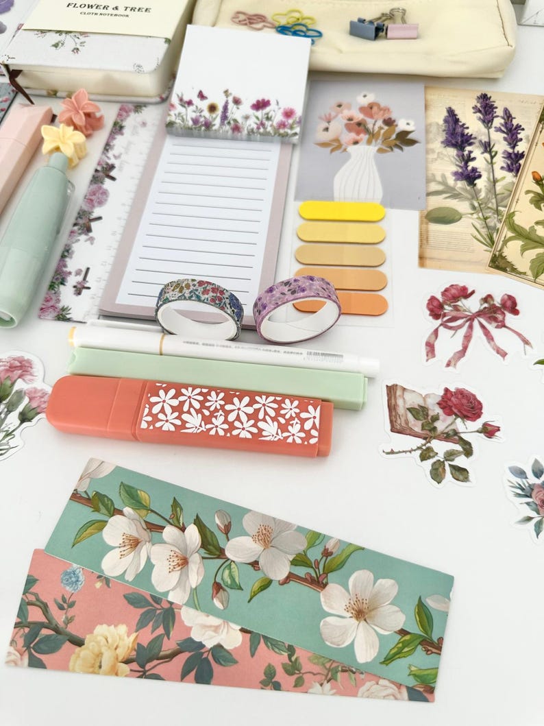 May include: A collection of stationery items with a floral theme. Includes notebooks, sticky notes, washi tape, highlighters, stickers, and decorative paper. The color palette features soft pastels and floral patterns, creating a cohesive aesthetic.