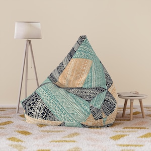 May include: A triangular bean bag chair featuring a patchwork design with teal, dark navy, and tan sections. Each section is covered in intricate white geometric patterns, including zigzags, diamonds, and linear stripes across the fabric.