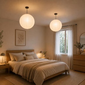 May include: A bedroom scene featuring two round, white paper pendant lights hanging from the ceiling. The room has a bed with beige bedding, a wooden frame, and a matching dresser. Two small lamps sit on the nightstands.
