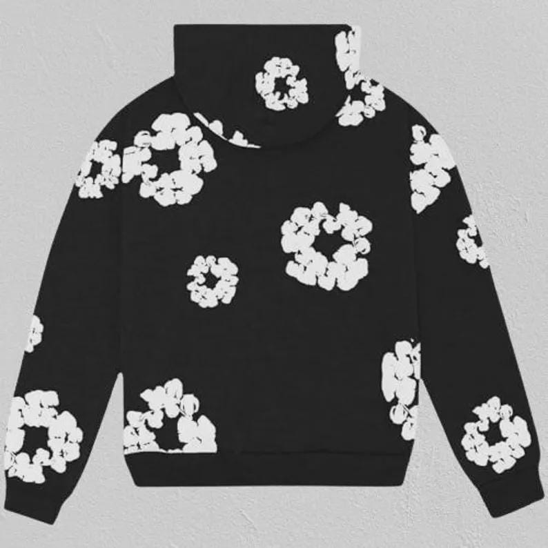 May include: Black hoodie with a white floral design. The sweatshirt has a high collar and is adorned with white, flower-shaped patterns across the front, back, and sleeves. The cuffs and hem are plain black.