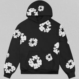 May include: Black hoodie with a white floral pattern. The hoodie has a drawstring hood, a kangaroo pocket, and white floral designs across the front, back, sleeves, and hood. The design is a repeating pattern of white floral shapes.