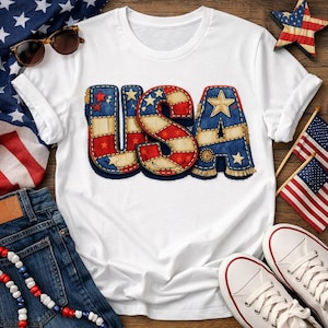 Peut inclure: T-shirt blanc avec le mot "USA" dans un motif patchwork. Les lettres sont rouges, blanches et bleues avec des étoiles, évoquant le drapeau américain. Le t-shirt est associé à un short en jean et des baskets blanches.