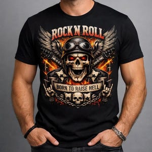 Pode incluir: Camiseta preta com um design gráfico com uma caveira usando capacete e óculos, asas e guitarras. O texto "ROCK N ROLL" e "BORN TO RAISE HELL" são exibidos. O design tem um tema de rock and roll ardente.