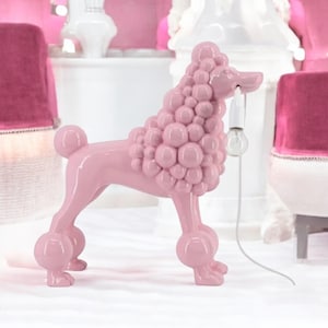 Può includere: Lampada a forma di barboncino rosa, con una lampadina in bocca. Il design è stravagante, con forme arrotondate che formano il pelo del barboncino. Questa lampada decorativa aggiunge un tocco giocoso a qualsiasi stanza, un elemento d'arredo unico.
