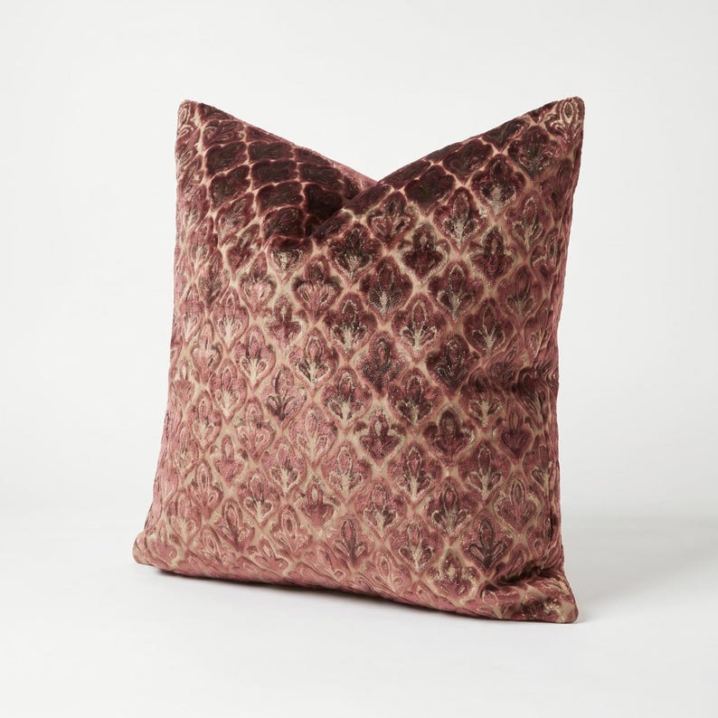 May include: A square throw pillow featuring a deep burgundy and dusty rose velvet fabric. The surface is adorned with a repeating, raised damask-style pattern that creates a textured, multi-dimensional appearance across the entire front face.