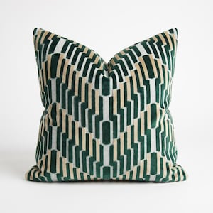 May include: A square throw pillow featuring a repeating geometric pattern in deep forest green, soft beige, and off-white. The design consists of vertical, interlocking rectangular shapes that create a textured, layered visual effect across the surface.