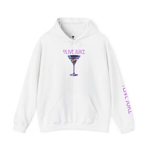 Puede incluir: Sudadera con capucha blanca con bolsillo delantero y capucha con cordón. La parte delantera presenta un gráfico de copa de martini con el texto "OLIVE JUICE" encima. La manga derecha tiene el texto ":LIVE JUICE" impreso verticalmente.