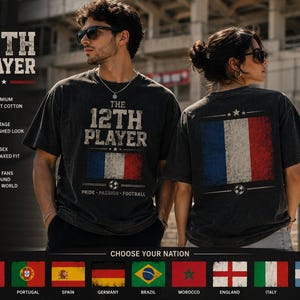Peut inclure: Un t-shirt gris anthracite à manches courtes avec le texte THE 12TH PLAYER et un drapeau français vieilli imprimé sur le devant et le dos. Le motif inclut une icône de ballon de football et les mots PRIDE PASSION FOOTBALL en style vintage.