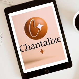 Op de afbeelding: Een zwarte tablet toont het woord "Chantalize" in een schreefletter, met een logo van een bruine bol, een witte "C" en een ster. Een kopje koffie en een stylus liggen op het witte oppervlak.