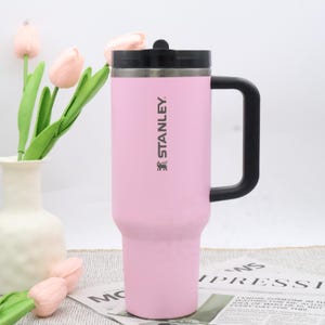 Pu&ograve; includere: Una tazza da viaggio Stanley rosa con manico e coperchio neri. La tazza presenta il logo Stanley. La tazza cilindrica ha una base affusolata ed &egrave; progettata per bevande calde o fredde. &Egrave; alta circa 23 cm.
