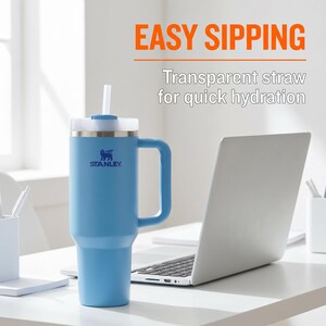 May include: A light blue Stanley tumbler with a white lid and handle, featuring a transparent straw. The text "EASY SIPPING" and "Transparent straw for quick hydration" are displayed. A laptop is in the background.