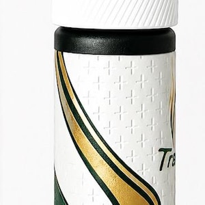 Könnte beinhalten: Ein Golfschlägergriff mit schwarzem Oberteil und weißen und schwarzen Akzenten. Der Griff hat eine weiße Basis mit einem sich wiederholenden Kreuzmuster und goldenen und grünen dekorativen Elementen. Das Wort "Tra" ist sichtbar.